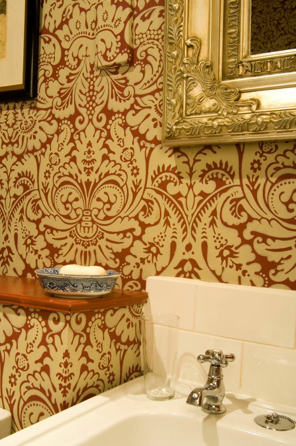 Bad med mønstret tapet på veggene i ekte Downton Abbey stil. Tapetet kommer fra britiske Farrow & Ball. Speil med tung, forgylt ramme kompletterer stilen.