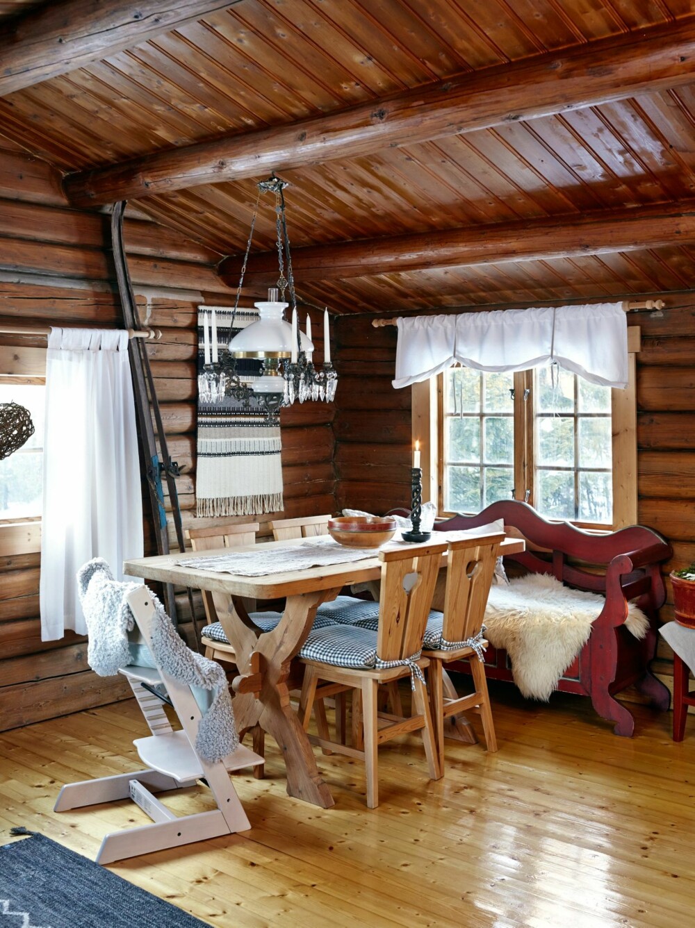 God atmosfære: Spisebordet, den røde sengebenken og stolene rundt bordet sto igjen etter forrige eier. Dette er nå blitt favorittplassen i stuen. De gamle hoppskiene til Linn Heges farfar har fått plass ved siden av et vevd teppe på veggen. Tripptrappstolen med en skinnfell tok de med hjemmefra. God atmosfære: Spisebordet, den røde sengebenken og stolene rundt bordet sto igjen etter forrige eier. Dette er nå blitt favorittplassen i stuen. De gamle hoppskiene til Linn Heges farfar har fått plass ved siden av et vevd teppe på veggen. Tripptrappstolen med en skinnfell tok de med hjemmefra.