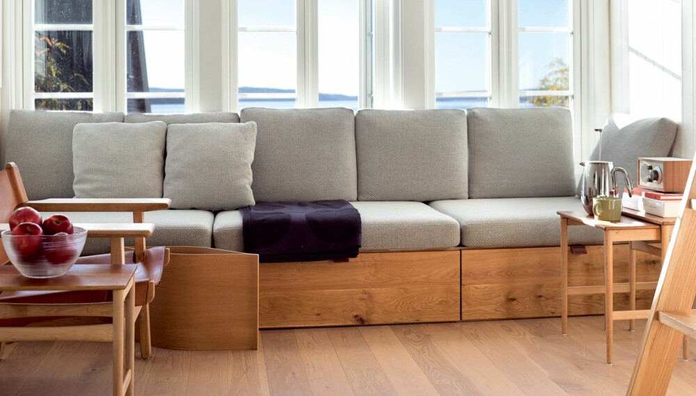 VELKOMPONERT: Sofaen er bygget fra vegg til vegg, en plassbesparende løsning. Her er det godt for to å lene seg mot hver sin vegg med en pute bak og bare nyte utsikten inn mot Bunnefjorden. Møbelsnekker Hans Petter Kjeldal Holst har bygget sofa, seng og skap og stige til hemsen.