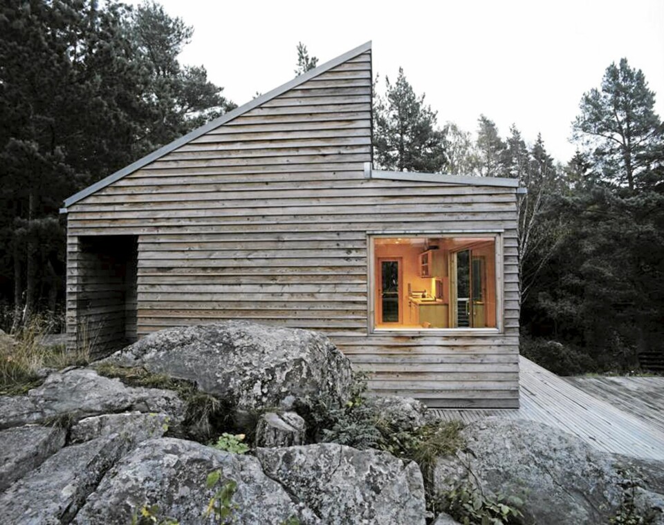 NØKTERN, SØLVGRÅ OG MED KUL UTEDUSJ: Fra siden ser vi den markante, høye profilen på Woody 35-hytta. Panelet gråner med tiden, og blir like grått som svabergene omkring. Her fra siden ser du utedusjen som har fått sitt eget rom på hjørnet helt til venstre.