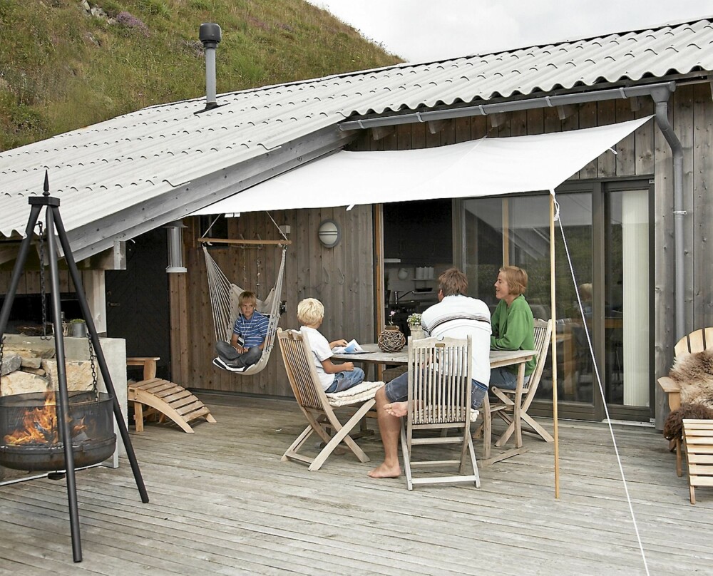 NATURLIG UTESTUE: Taket er trukket over en del av terrassen med en utebod i bakkant. En enkel solskjerm gir ly for sola.