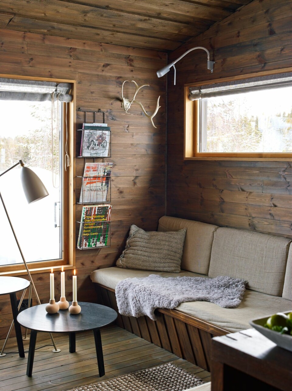 Lunt og lyst: Vinduet er plassert høyt over sofabenken for å danne en lun krok mot det store vinduet. Puten har Ellen strikket av restgarn. Geviret fulgte med hytta. Lampe, bord og matte fra Hay. Sofaen er trukket med linstoff.
