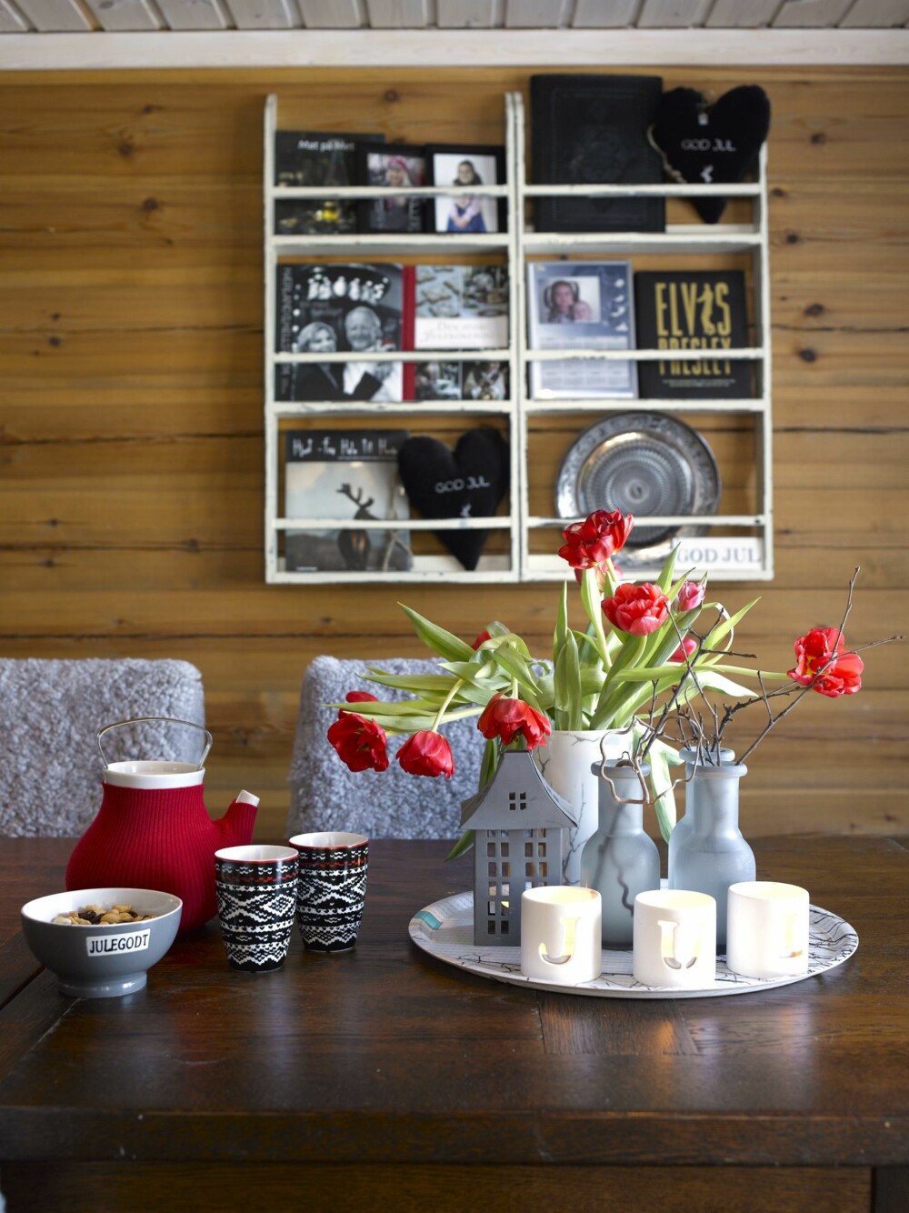 NY VRI: I den hvite tallerkenhyllen over spisebordet har hytteeierne plassert kokebøker. De kjøpte hyllen med tanke på nettopp å oppbevare bøker og bilder. De røde tulipanene er som er spredd rundt i interiøret er viktige for Monica i julen.
