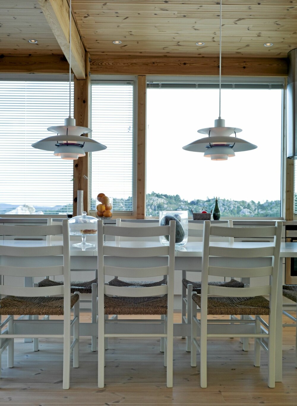 KJØKKENHYGGE. Hvitt kjøkkenbord fra Ikea, jærstoler Aksel fra Hjelmeland og PH-lamper fra Lois Poulsen.