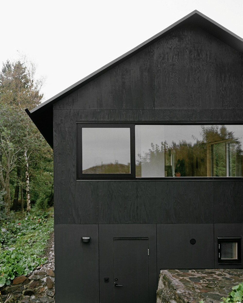 ARKITEKTENS KOMPROMISSLØSE DESIGN: Måten gavlen er delt opp skaper en grafisk, visuell effekt. Alle yttervegger er tjæret slik som gamle trebåter ble. ARKITEKTENS KOMPROMISSLØSE DESIGN: Måten gavlen er delt opp skaper en grafisk, visuell effekt. Alle yttervegger er tjæret slik som gamle trebåter ble.