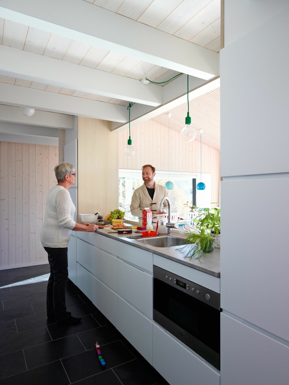 PØLSEBODEN: Åpning mot
stuen gjør at kjøkkenet fungerer som en real pølsebod når storfamilien samles. Med på kjøpet følger en flott sjøutsikt. Innredning fra Kvik. Benkeplate av grå laminat. (FOTO: Ragnar Hartvig) 