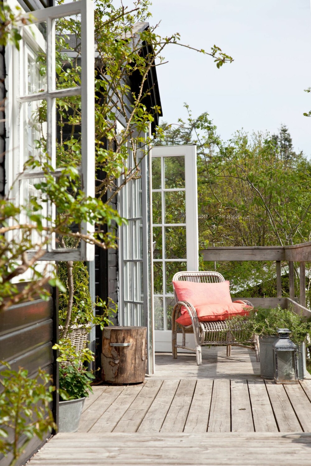 EN PLASS I SOLEN: Langs huset står flere små sittegrupper, og det fins også en plass i solen under klatrerosen, som blomstrer fra juni til frosten kommer. Møbler, tepper og puter fra Tine K Home.