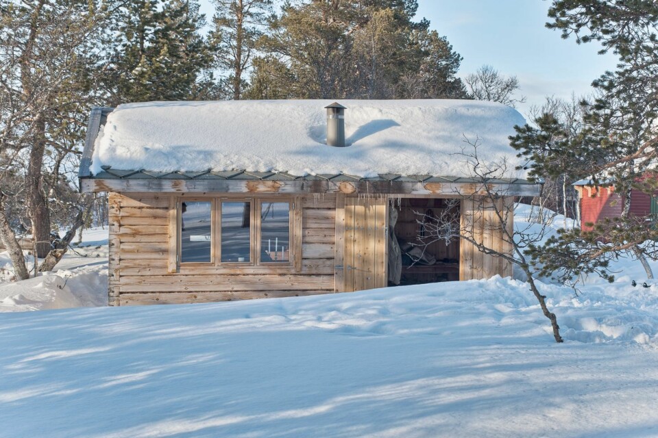 MINDRE ANNEKS: Til høyre i bildet, ikke langt fra den vakre tømmerhytta har hytteeierne satt opp et anneks, som byggeteknisk og stilmessig står i skarp kontrast til hovedhytta.