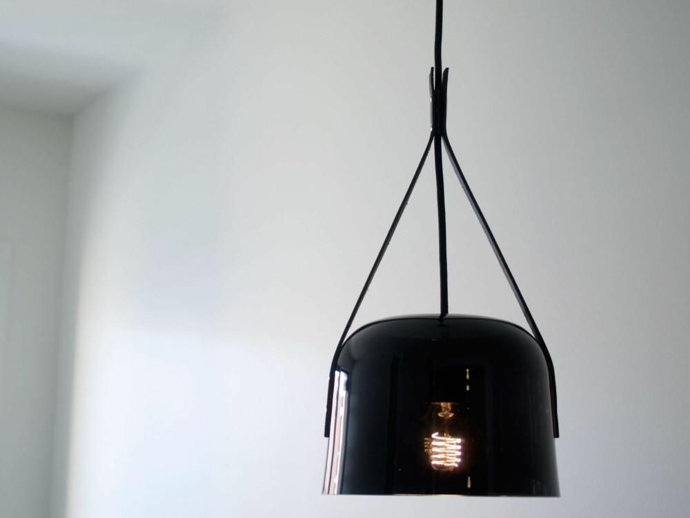MØRKT LYS: In Darkness har  Øyvind Wyller kalt lampen som ble vist på Wallpaper Handmade-utstillingen. Stemningen skapes av en mørk glass-skjerm, skinnremmer og en glødelampe i enden av en tekstilkledd ledning. Pendelen er laget i samarbeid med Magnor.