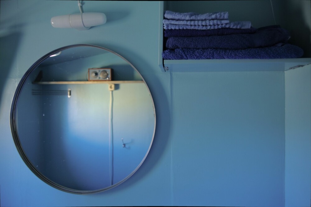 GAMMELT NYTT: Den lange trehyllen (i speilet) er en eikeplanke eier hadde liggende. Den lyseblå hyllen er gamle hyller som ble malt i samme farge som veggen og satt sammen på en ny måte.