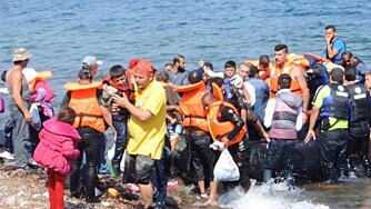 REDDET I LAND: Her bærer norske Magnus Østebrød et flyktningbarn i land på Lesbos. Daglig kommer mellom 30 og 50 overfylte gummibåter med flyktninger til den greske øya.