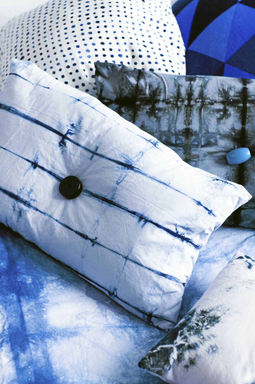 MODERNE UTTRYKK: Batikk skaper et moderne og avslappet uttrykk. På puten med den blå knappen er det brukt svart batikkfarge på grå tekstil. MODERNE UTTRYKK: Batikk skaper et moderne og avslappet uttrykk. På puten med den blå knappen er det brukt svart batikkfarge på grå tekstil.