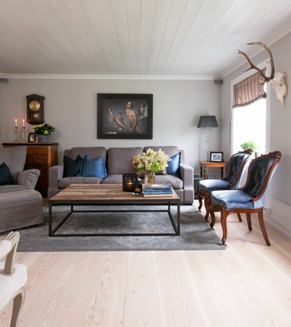 HELHETLIG. Bildet over sofaen er malt av Monika Helgesen. Veggene er tapetsert i en lys, grå tone fra Fargerike. Sofaen er designet av Halvor og er en del av hans kolleksjon for Bohus. De blå stolene har beholdt det opprinnelige stoffet.