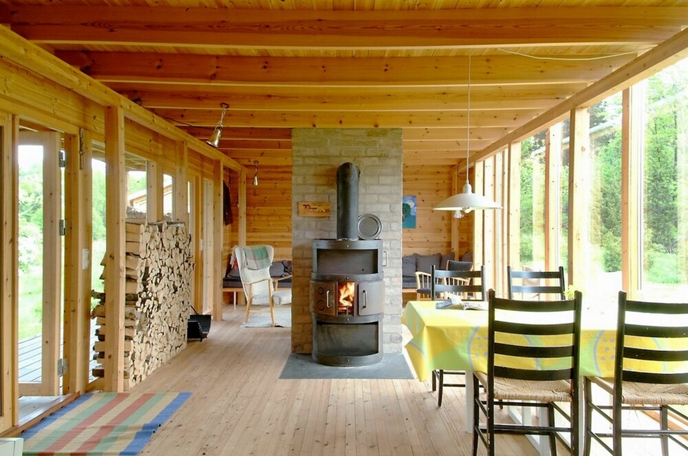 STUEROM I DET FRI: Peisovnen er det suverne sentrum i stuedelen av sommerhytta. Her er det også fullstendig åpent utsyn til begge sider. STUEROM I DET FRI: Peisovnen er det suverne sentrum i stuedelen av sommerhytta. Her er det også fullstendig åpent utsyn til begge sider.