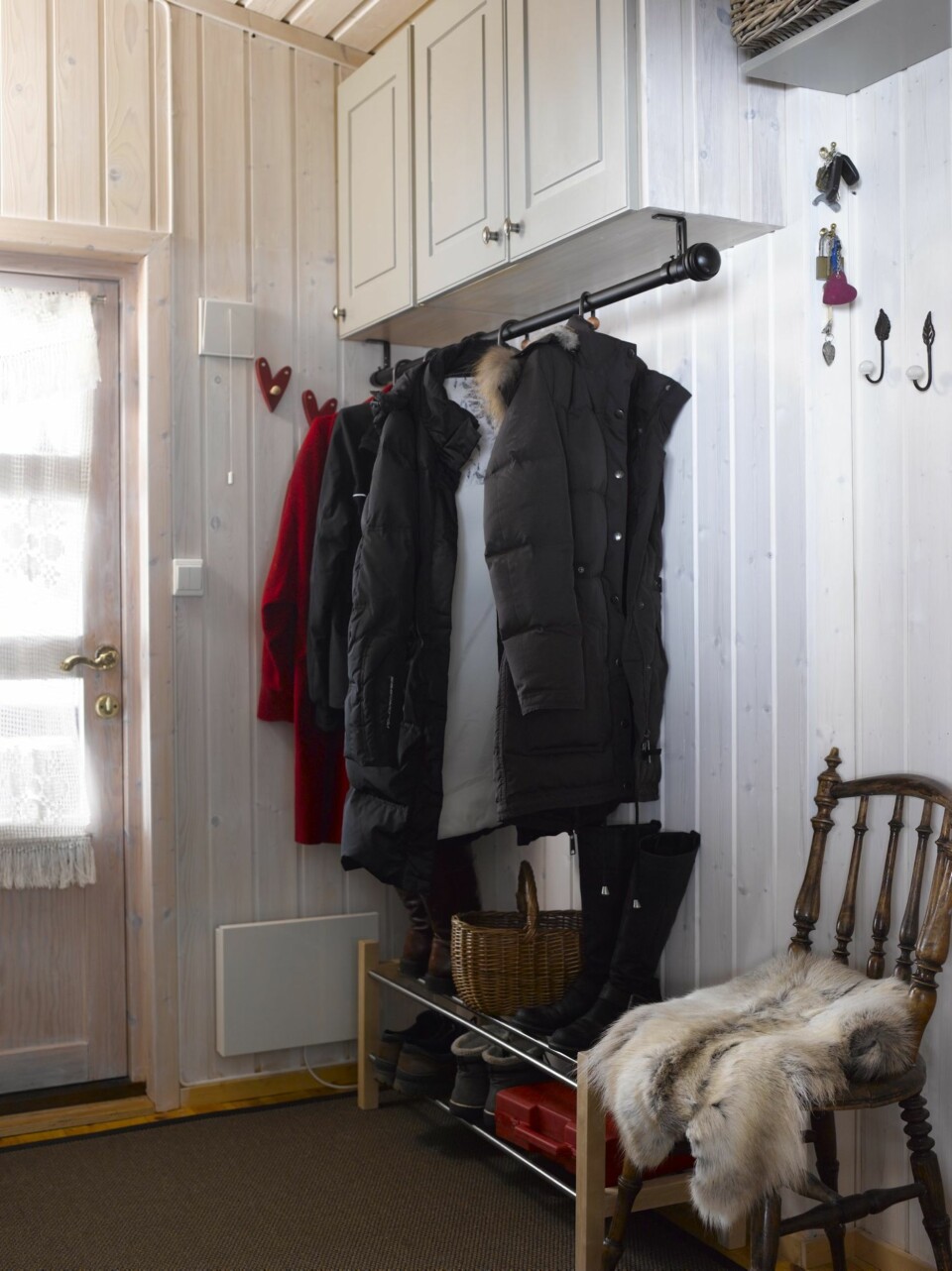 GJENBRUK: Overskapene fra det gamle kjøkkenet ble malt i samme farge som det nye og hengt opp på veggen i gangen. De er gode til oppbevaring av luer, votter og skitøy. Stangen under er en gammel gardinstang fra stuen.
