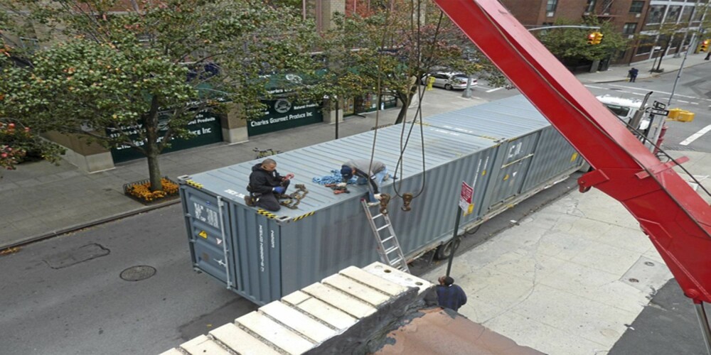 HØYT HENGER DE: En heisekran heiser containerene på plass, klare til å settes sammen.