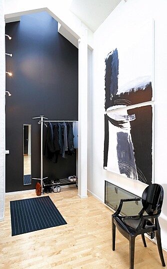 RETT INN. Ved inngangspartiet er det satt opp en enkel garderobe ved den svarte endeveggen. Bildet er "hjemmemalt", stol fra Philippe Starck.