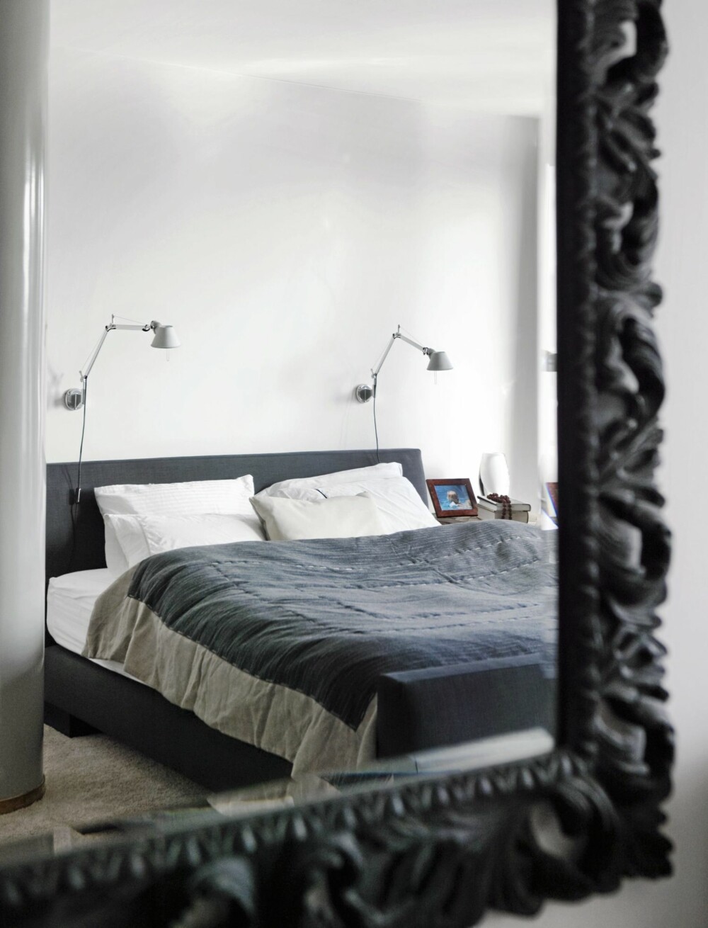 FRA SOVEROMMET: Speilet med kraftig utskåret ramme bryter med det minimalistiske soveromsinteriøret. Den kommer fra Magazin. Lamper fra Flos.
