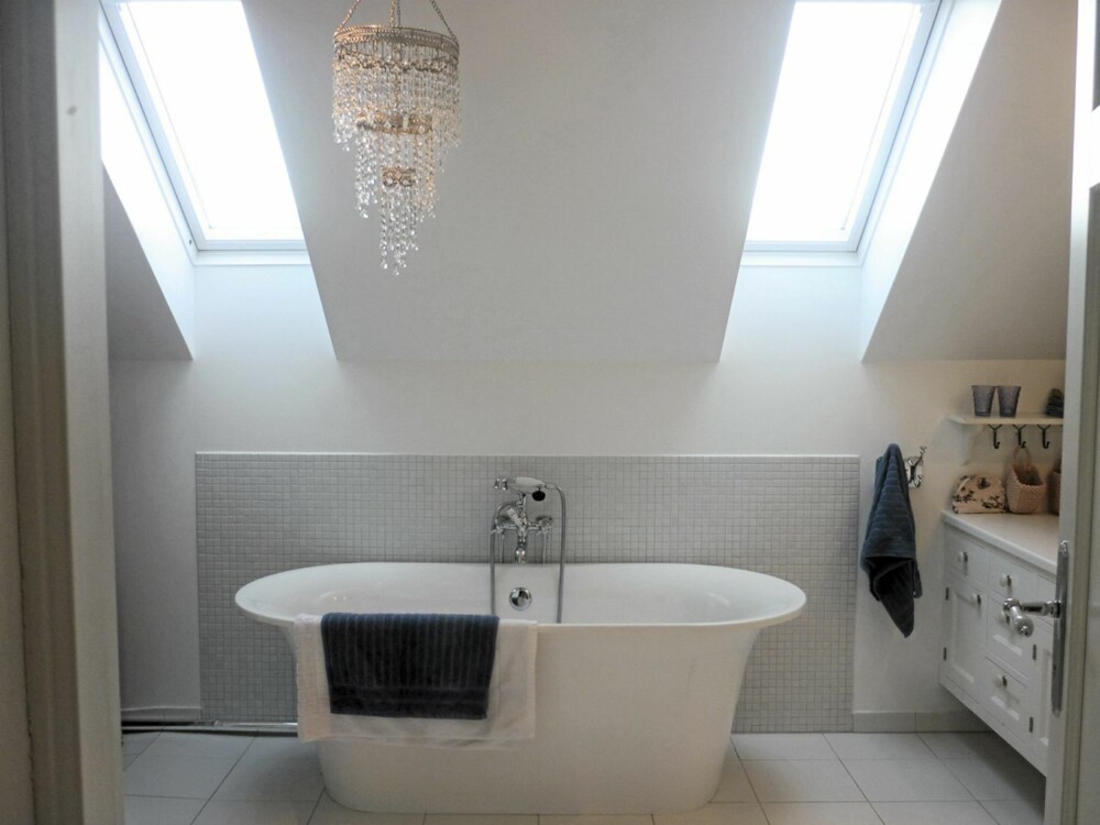 Badet har natulig lys fra takvinduene og et stort badekar midt i rommet.
