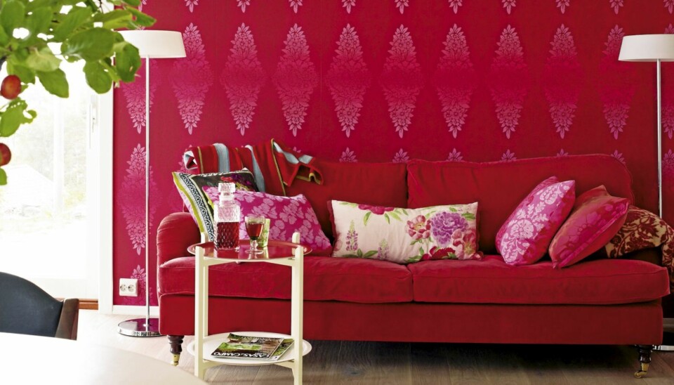 ROSENRØDT. Det er friske farger i designerens hjem. Sofaen står på kjøkkenet og tapetet fra Designers Guild fant Kjersti på salg i London. Sofa fra Bohus og lamper fra Lyspunktet.