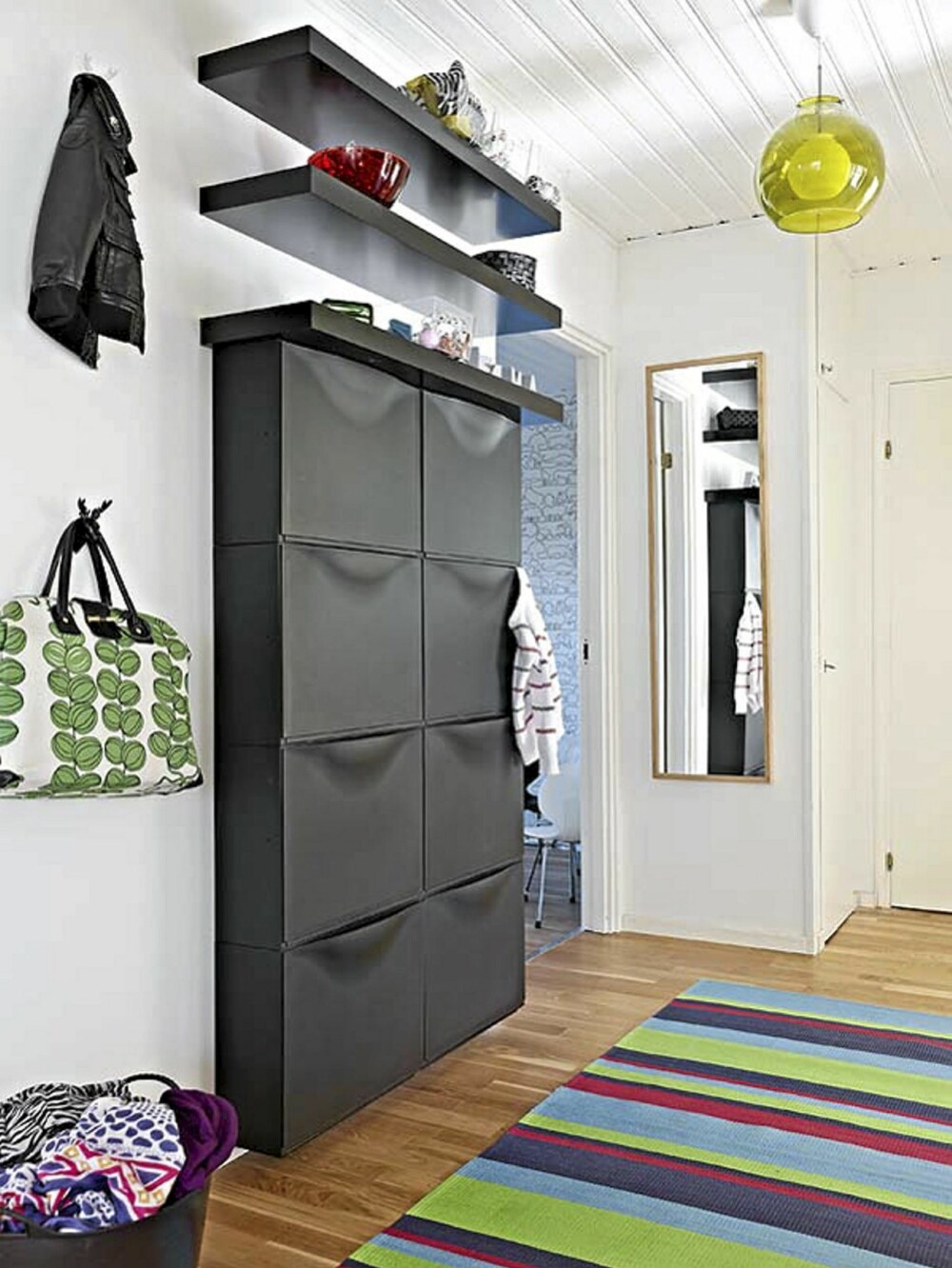 Skoskapet fra Ikea er stort, svart og finnes i svært mange hjem. Men mot hvit vegg, kombinert med en fargerik taklampe og mot en festelig løper på eikeparketten, blir skoskapet nesten skulpturelt i formen. Skoskapet fra Ikea er stort, svart og finnes i svært mange hjem. Men mot hvit vegg, kombinert med en fargerik taklampe og mot en festelig løper på eikeparketten, blir skoskapet nesten skulpturelt i formen.