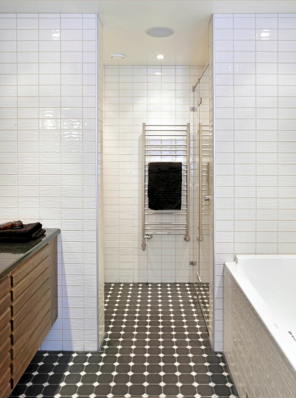 TO SONER: Når man kommer inn på badet, ser man verken toalett Eller dusj. De funksjonene er trukket tilbake og skjermet bak hver sin
halvvegg. Den vegghengte innredningen strekker seg fra vegg til vegg.
