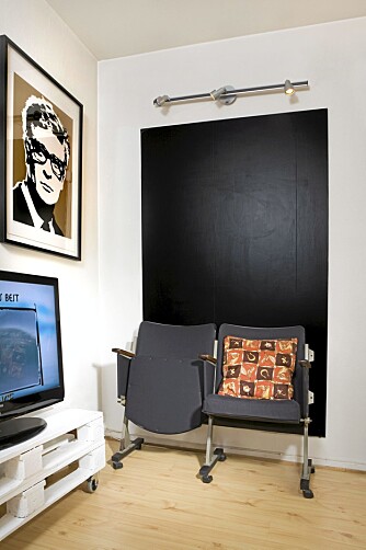 KUNSTVERK: Michael Caine, som henger på veggen til venstre, er et kunstverk av Conrad Leach. Bak kinostolene mine har jeg hengt opp en svartmalt mdf-plate. Jeg har alltid ønsket meg en svart vegg, men i denne lille leiligheten ville nok en hel vegg blitt litt mye. TV-bordet har jeg lagd av paller som jeg har sagd i to, malt hvite og satt hjul på. KUNSTVERK: Michael Caine, som henger på veggen til venstre, er et kunstverk av Conrad Leach. Bak kinostolene mine har jeg hengt opp en svartmalt mdf-plate. Jeg har alltid ønsket meg en svart vegg, men i denne lille leiligheten ville nok en hel vegg blitt litt mye. TV-bordet har jeg lagd av paller som jeg har sagd i to, malt hvite og satt hjul på.