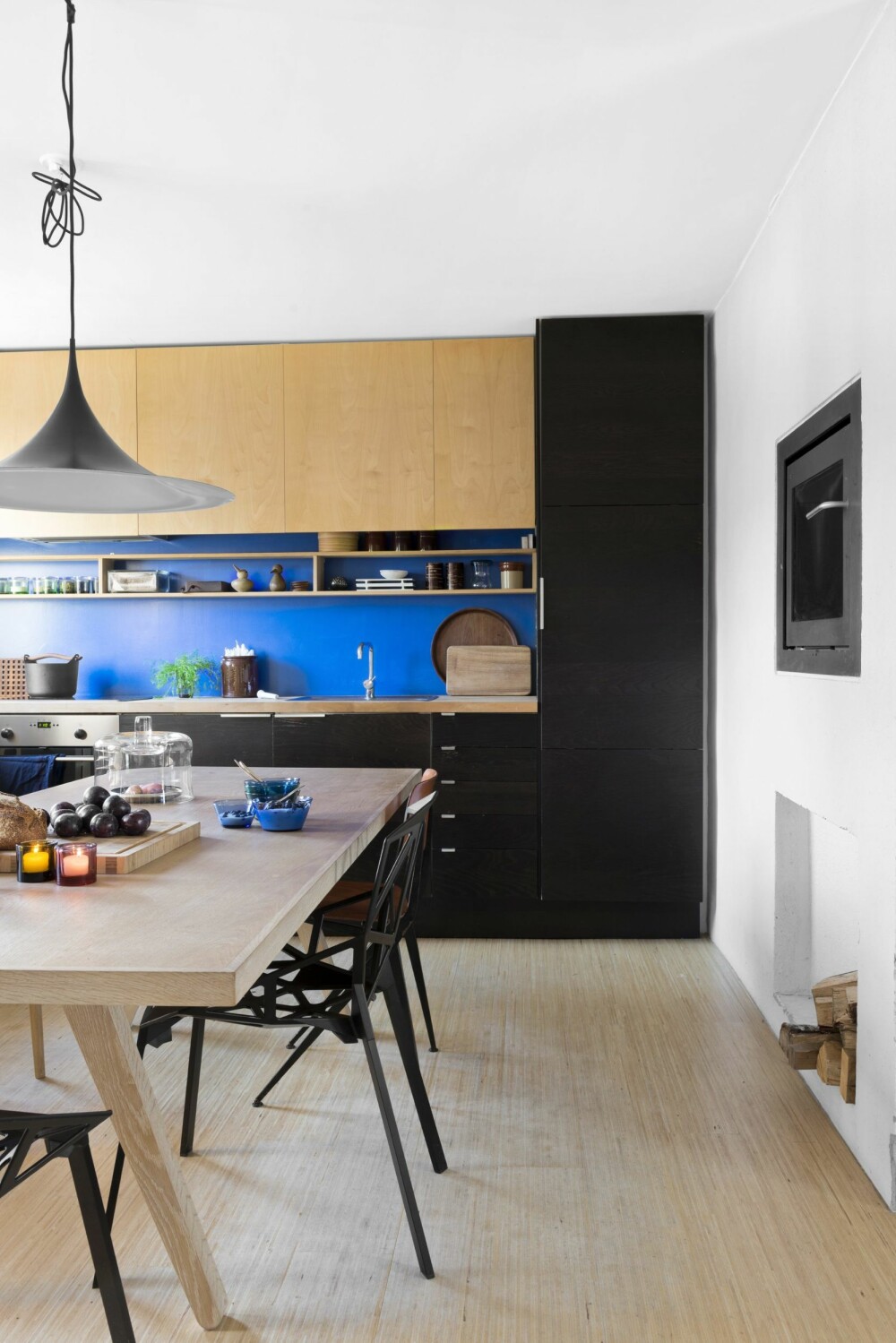 FARGESTERKE FLATER: Kjøkkeninnredningen dekker hele kortveggen, fra hjørne til hjørne. Løsningen gir maksimal gulvplass – et must for å nyte godt av kjøkkenets mest sentrale flate: familiens digre eikebord. Den mørkbeisede innredningen er fra Ikea, mens resten er spesialbygd. 