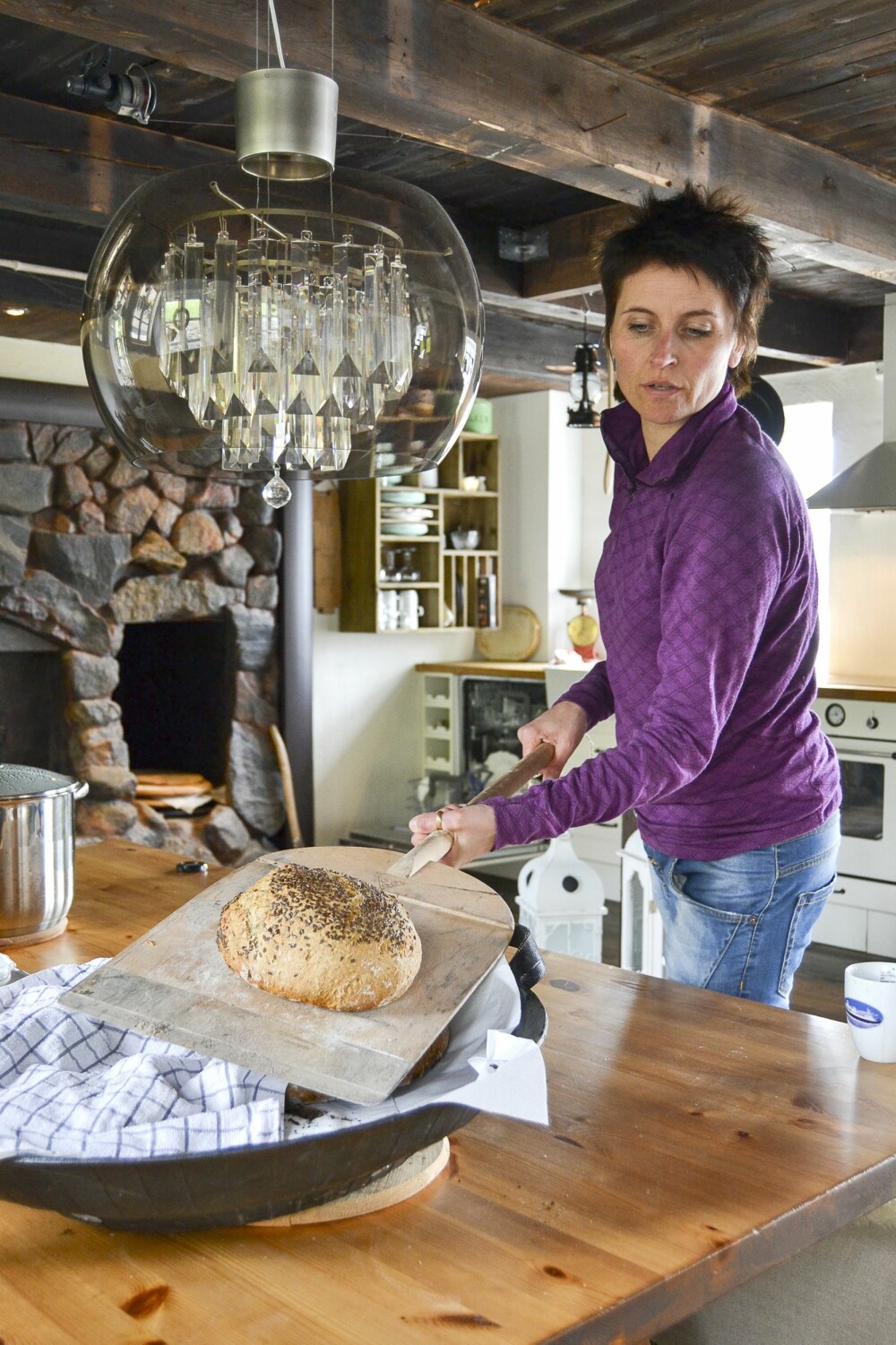 BRØD RETT FRA OVNEN: Bente og familien bruker bakerovnen i bøkkerverkstedet så ofte de kan. Her er det Bente som er i sving med bakespaden og tar ut nystekte brød fra ovnen. 