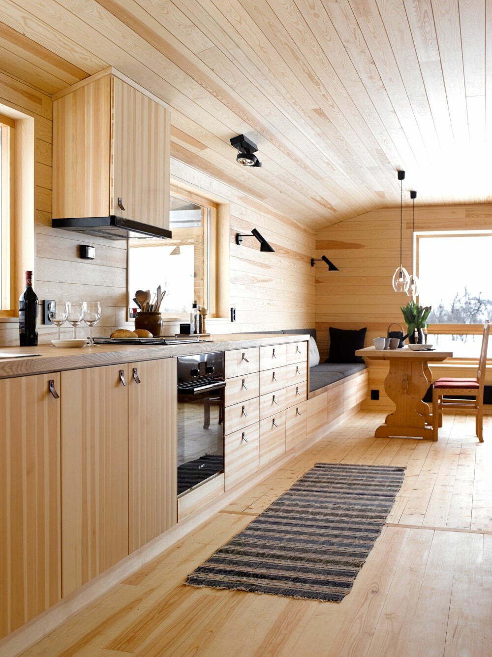 SITTEBENK: Kjøkkenbenken trappes 
ned og blir til sittebenk ved spisebordet. Ensartet materialbruk på innredning, gulv, vegg og tak gir et rolig uttrykk.