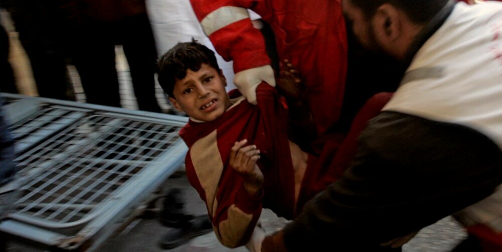 USKYLDIG OFFER: Palestinere bærer en skadet gutt i sikkerhet.
