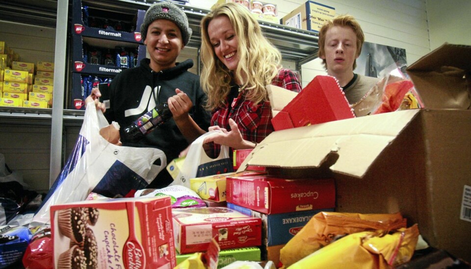 KAKEMIKS: Desember er høytid for matutdeling på Slumstasjonen i Oslo. Medarbeider Silje Maria Erland (i midten) er glad for å få noen hjelpende hender. Her bistår elevene Hayden Aqueel (t.v.) og Harald Helberg fra sosiallinja ved Rønningen folkehøgskole med å pakke ned kakemiksposene fra Klikk Helse i julematposene som skal gis bort.