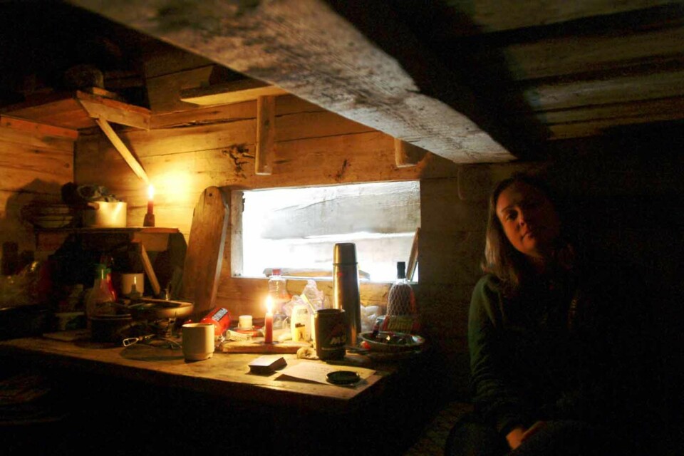 KVELDSSTEMNING: Et typisk krypinn på de nordre breddegrader, en trang jakthytte med planker foran vinduene som beskyttelse mot isbjørner. Iblant sitter de nedsnødd i dagevis. - Da spiller vi poker og leser bøker.