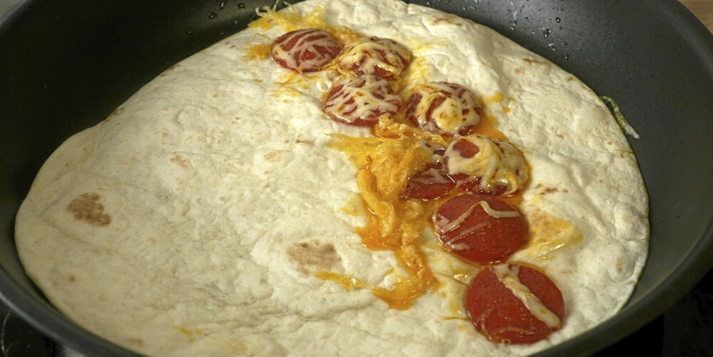 2. Løsne osten og pølsene fra pannen, og legg en lefse under.