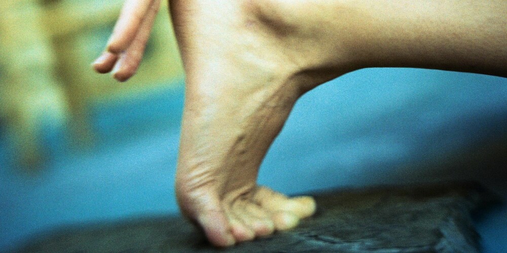 Woman crouching, close-up of hand on heel Woman crouching, close-up of hand on heel