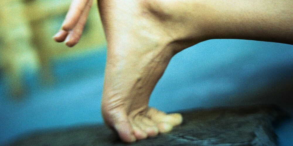 Woman crouching, close-up of hand on heel