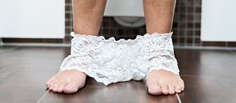 Suggestive close up view of the bare legs and feet of a woman with her sexy lacy panties lying on the bathroom floor around her ankles