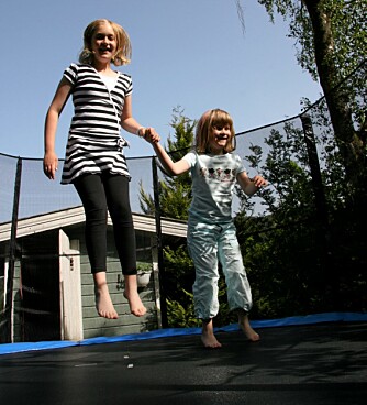 TRYGGHET: Viktoria har det moro på trampolinen når storesøster Ida, den eneste av barna som ser, holder hånden hennes. (Foto: Hege Opseth)