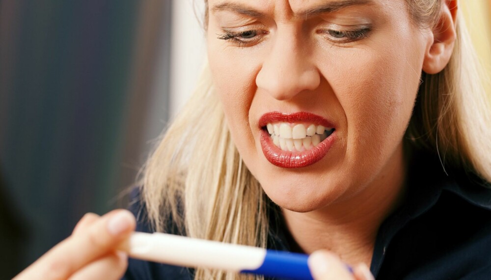 Woman looking at a pregnancy test being disappointed and angry upon the result
