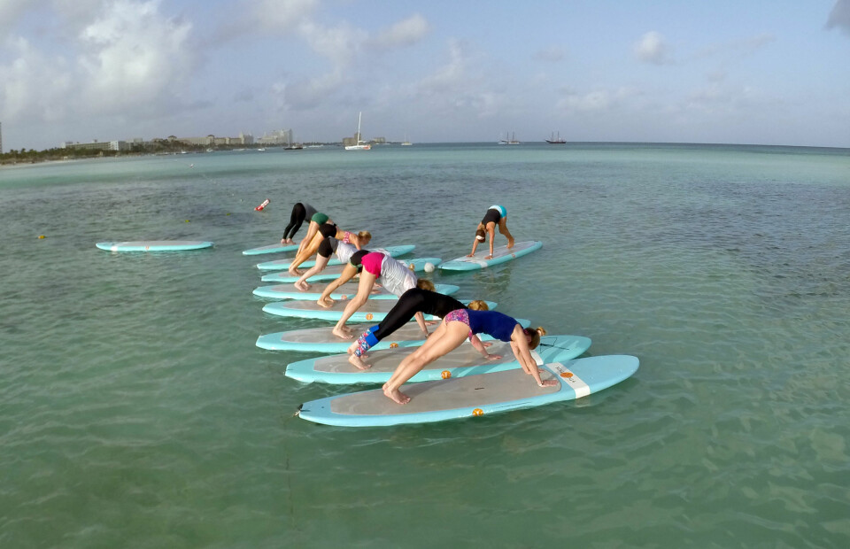 SUP-yoga, eller Stand Up Paddleboard Yoga om du vil, er veldig gøy! Men enkelt skal jeg ikke påstå å si at det er. Her gjør vi en downward dog så godt som vi kan. Jeg eier den grønnkledde rumpa bak der.