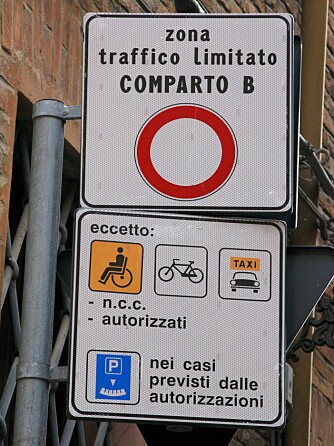 SKYGG UNNA: Slike skilt brukes i flere italienske byer. Noen ganger er forbudssirkelen mye mindre, og det er mye mer tekst - og følgelig ganske vanskelig å forstå for en turist som ikke kan italiensk. Ofte tas det automatisk bilde av alle som kjører inn i en slik sone. FOTO: Wikimedia Commons/Alain Rouiller