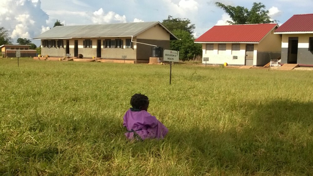 LIVETS SKOLE: «Education is wealth». Skilt ved en skole i Luwero på den ugandiske landsbygda. Er det det hun sitter og funderer på, den lille jenta?