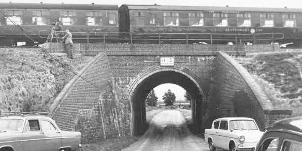 Her, ved lille Bridego Bridge i Buckinghamshire, skjedde det myteomspunne togrøveriet. Bildet er tatt på et senere tidspunkt, med et annet tog på broen. Det «ekte» toget sees ved Cheddington stasjon på det lille bildet.