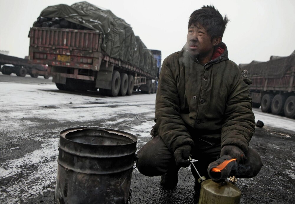På en parkeringsplass ved byen Fukang i Xinjang forsøker en trailersjåfør å reparere motoren sin med de midlene han har for hånden. I en bitende kulde.