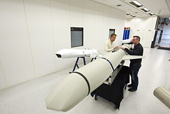 Christian Kjølseth og Jens Gjestvang med NSM-missilet på laboratoriet på Kongsberg. I bakgrunnen en modell av JSM.