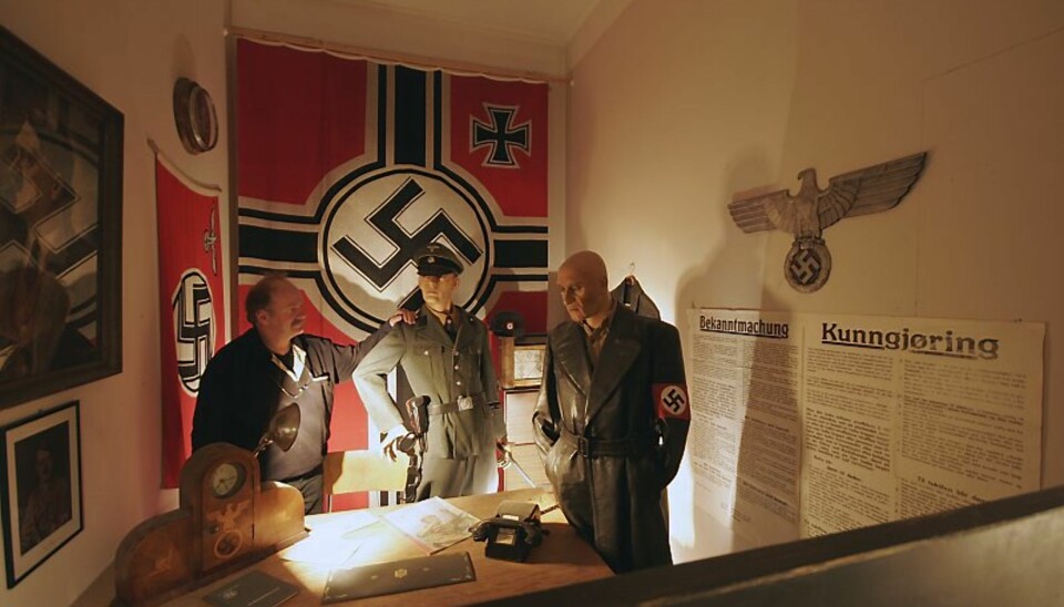 NATURTRO:Det er noe skummelt over det naturtro Gestaporommet med det svære naziflagget, nazisymbolet og plakaten med sin Bekanntmachung. Du føler at her har dødsdommene sittet løst. En av personene på bildet hører ikke naturlig hjemme i dette tidsbildet. Ser du hvem?