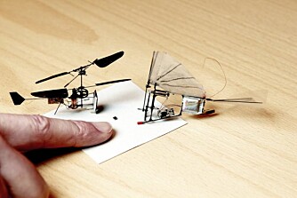 KNØTTSMÅ: Verdens minste helikopter, "Nanoflyer II" på 0,89 gram (t.v.) og verdens minste ornitopter, "HUmmer", 1,1 gram. "Fluelorten" på papiret er faktisk et vedeokamera som skal bygges inn i mikrofarkostene.