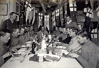 6. juni 1911. Scott fyller 43 år. Han sitter ved bordenden. Ekspedisjonens outsidere, Lawrence Oates og Tryggve Gran, står til venstre og høyre.