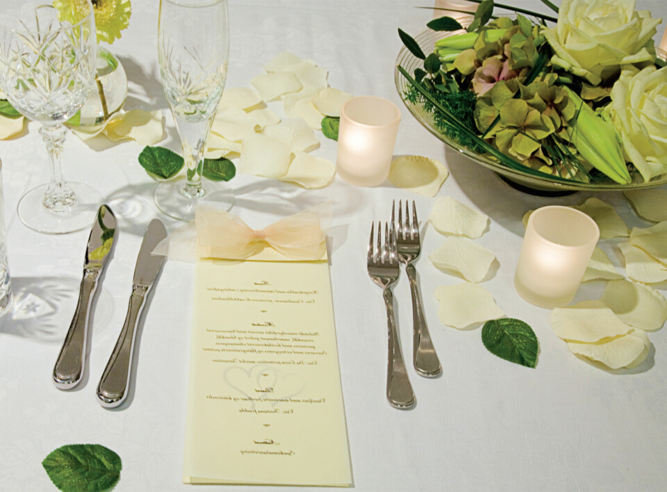 KLASSISK: Roseblader, kubbelys, telys, perlerekker,
offwhite gaveesker, servietter i offwhite med gulltrykk av brydeparets navn. I denne blomsterdekorasjonen fra Kreativ Flora er det brukt blant annet roser, hortensia og olivenblader. Olivenblader kan også benyttes til å strø på bordet som en dekoreffekt. Elfenben og gull passer perfekt til klassiske bryllupslokaler, og setter alltid rammen for et tidløst bryllup.