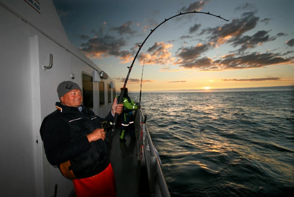 FAST FISK: Jan Ring kjører storfisk, mens midnattssola dupper i horisonten.